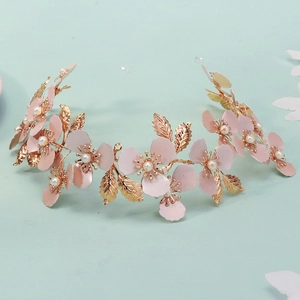 Detalle de una diadema de novia hecha a mano con flores rosas y hojas doradas