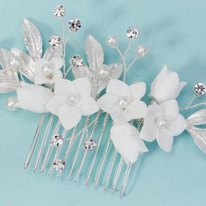 Close-up of handmade white ceramic flowers and crystal beads on a silver bridal hair comb