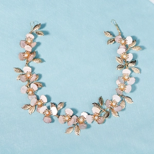 Diadema de novia artesanal con flores rosas, hojas doradas y perlas sobre fondo azul