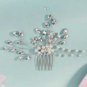 Detailed view of silver bridal hair comb with rhinestones and white pearls on blue background