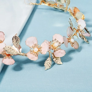 Detalle de pétalos de flores rosas con perlas y hojas doradas en una diadema de novia