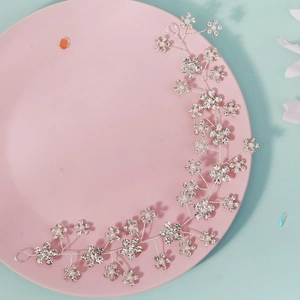 Détail de vigne à cheveux argentée pour mariée avec strass et perles sur plateau rose