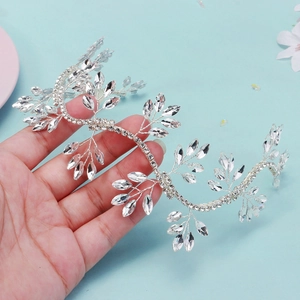 Close-up of flexible silver bridal headband with crystal leaves held by hand