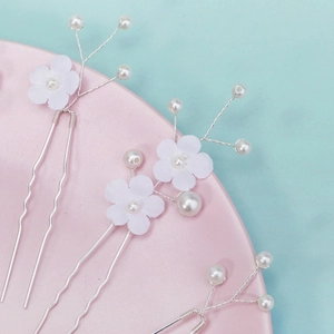Vue détaillée de trois épingles à cheveux de mariée avec fleurs en tissu blanc et perles