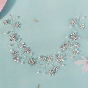 Détail de vigne à cheveux mariée argentée avec strass fleuris et perles blanches