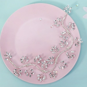 Silver bridal hair vine with marquise rhinestones on a ceramic plate with blue background