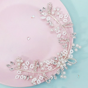 Close-up of handmade bridal headband with white pearls and crystals on silver wire vine