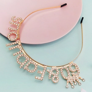 Detail of Bride To Be gold headband with sparkling rhinestones and crown on pink tray