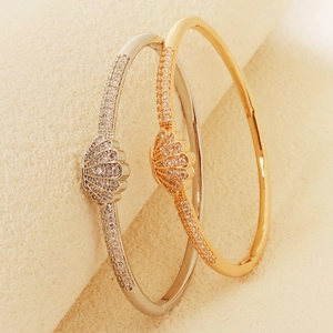 Close-up of gold and silver shell-shaped open bangles with sparkling zircon inlay