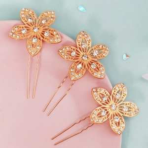 Detailansicht von drei goldenen Blumen-Haarnadeln mit glitzernden Strasssteinen für Bräute