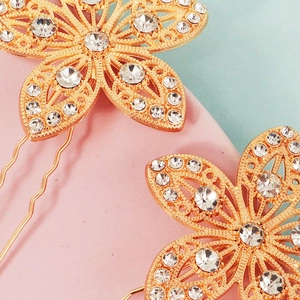 Nahaufnahme goldener Haarnadeln mit Blumenmuster und glitzernden Strasssteinen