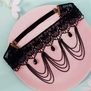 Détail d'un choker en dentelle gothique avec glands en chaîne noire et perles résine