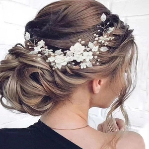 Detail of bridal hair vine with white ceramic flowers, pearls, and silver leaves on hair