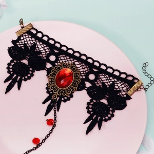 Macro view of gothic black lace choker featuring a large red gemstone and bronze metal details
