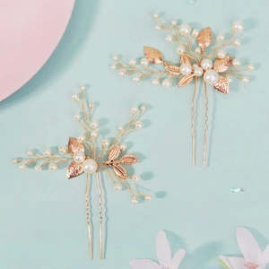 Close-up of gold wire bridal hair pins with white pearls and hollow leaf details