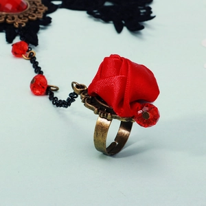 Macro shot of Gothic red fabric rose and bronze ring on elegant black lace bracelet