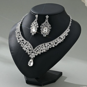 Detailed view of silver luxury rhinestone necklace and earrings on a black neck display