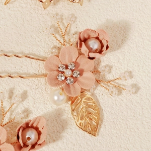 Makroaufnahme pinker Stoffblumen mit Kristallmitte und goldenen Perlen-Haarnadeln