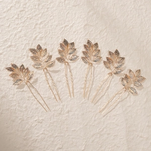 Detailed close-up of six gold leaf bridal hair pins with intricate metallic textures