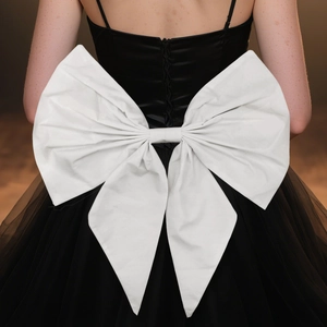 Detail of a large white handmade bow and lacing on the back of a black wedding dress
