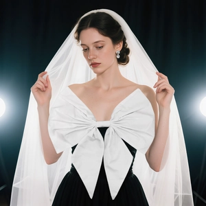 Elegant black strapless dress featuring a large white satin bow and long bridal veil