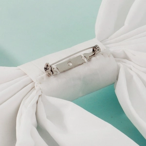 Detail of the silver metal safety pin attachment on the white fabric wedding bow accessory