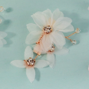 Detail of white double-layered mesh flower hair clip with sparkling rhinestone center and gold wire
