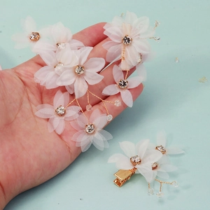 Detail of white double-layer mesh flower hair clip with sparkling rhinestones and gold wire