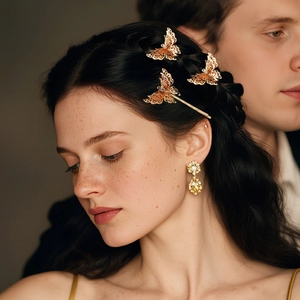 Detailed view of golden butterfly hair clip and yellow gemstone drop earrings on model