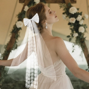 Détails de broderie et dentelle sur un voile de mariée blanc avec nœud élégant