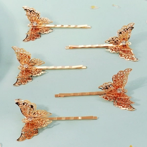 Detail of five golden butterfly hair clips with intricate filigree and white rhinestones