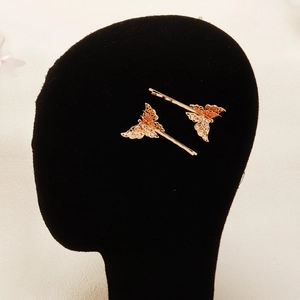 Detail of golden butterfly hair clips with hollow wings and inlaid white rhinestones