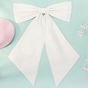 Detail shot of a large white fabric bow brooch with long ribbons for wedding dress decoration