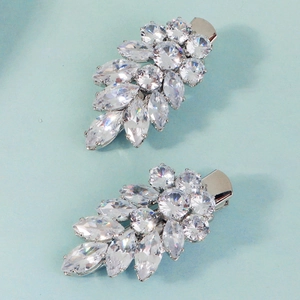 Detail shot of silver leaf hair clips with marquise-cut zircon stones on a light blue background