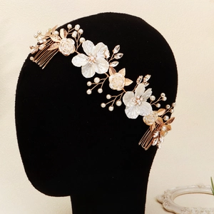 Detail of bridal hair comb with white 3D flowers, pearls, and crystals on gold wire