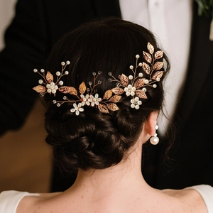 Elegant bridal hair comb with gold leaves, white pearls and crystals on a low bun hairstyle