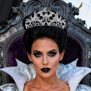 Close-up of gothic silver bat crown with rhinestones worn by a model on a purple throne