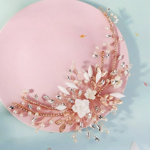 Dettaglio della fascia da sposa dorata fatta a mano con fiori bianchi e perle di cristallo