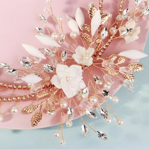 Elegante fascia da sposa con fiori fatti a mano, foglie dorate e perle su vassoio rosa