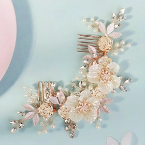 Detail of bridal hair comb featuring white silk flowers with pearls and gold wire details