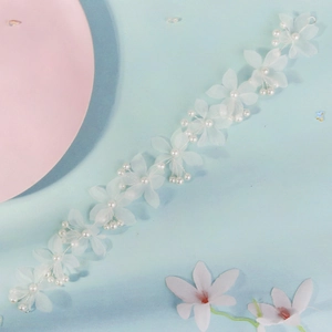 Vue détaillée des fleurs en tissu de soie blanche et perles sur le bandeau de mariée