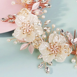 Elegant bridal headpiece with white shell flowers, pearls, and gold leaves on blue background