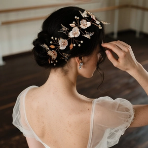 Détail de coiffe de mariée avec fleurs blanches, perles et accents de papillons ciselés