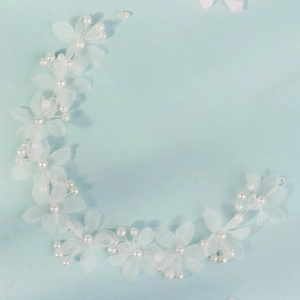 Détails de fleurs en soie blanche faites main et perles sur vigne de cheveux de mariée