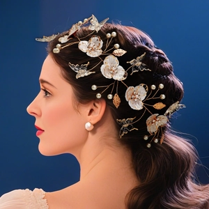 Détail d'un bandeau de mariée avec fleurs blanches, papillons et feuilles dorées