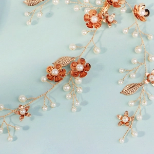 Détail d'un accessoire de coiffure de mariée doré fait main avec perles et fleurs