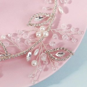 Close-up of bridal headband with rhinestones, pearls and silver leaf details