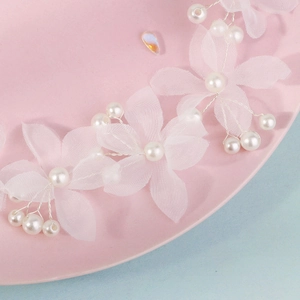 Détail d'un bandeau de mariée avec perles blanches et fleurs en tulle sur plat rose