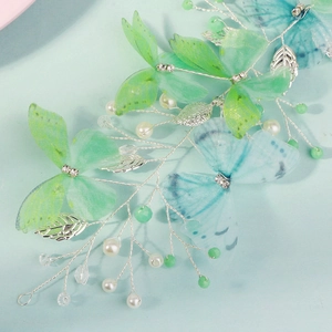 Close-up of handmade green tulle butterflies with pearls and crystals on silver wire