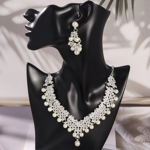 Elegant bridal jewelry set with pearl necklace and drop earrings on black display stand